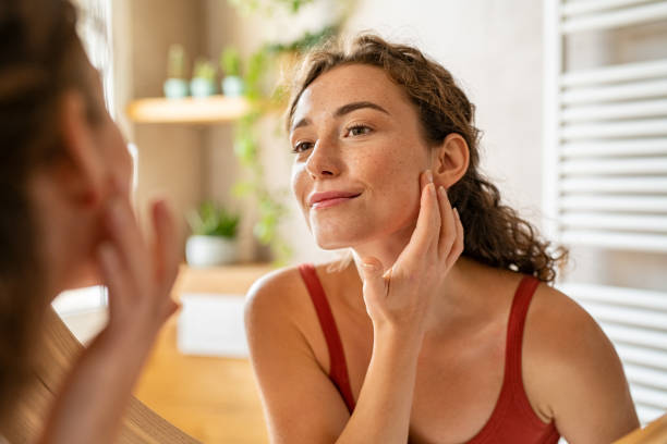 Woman checking her skin after putting skin care products