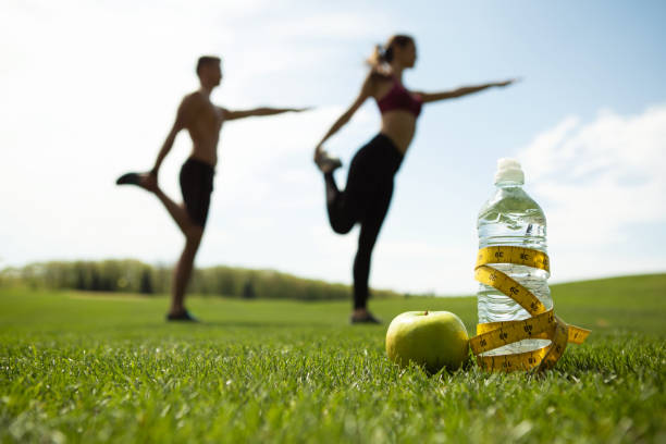man and woman working out in nature with a fruit and water bottle ready
