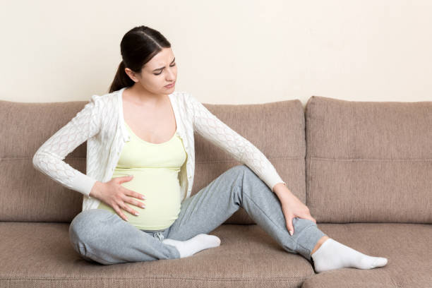 pregnant woman sitting down massaging her ankles due to joint pain