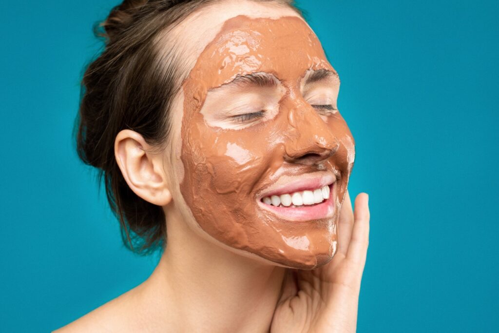 Woman applying mask on her skin as part of her skin care secret